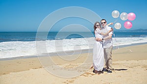 Young romantic couple with balloons on the beach