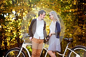 Young romantic couple bearded man and attractive woman at tandem bicycle in autumn park or forest.