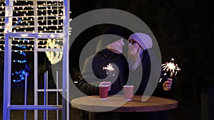 Young romantic couple having fun outdoors in winter before Christmas with sparklers in hands.Enjoying spending time