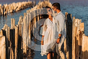 Young romantic couple hugging and about to kiss in beautiful sunset. Portrait of a couple in love at sunset by the sea.