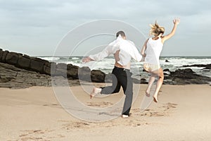 Young romantic couple jumping on the beach at sunrise