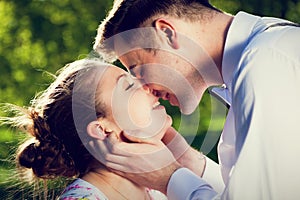 Young romantic couple kissing with love in summer park.