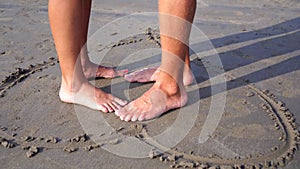 Young romantic couple in love on the beach. Drawing of a heart on the sand