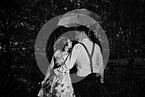 Young romantic couple in love flirting in rain. Black and white