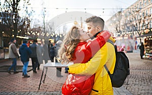 Young romantic couple in love kissing, hugging, walking on the street, wearning in bright down jackets. urban background