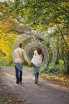 Young romantic couple in love walking in the autumn park holding hands