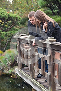 Young romantic couple standing on the bridge looking on the water