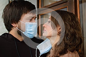 Young romantic loving couple wearing a protective face mask and staring at each other& x27;s eyes, St. Valentine& x27;s day during