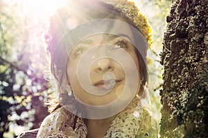 Young romantic woman with wreath of dandelions on the head in su