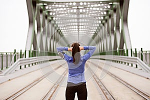 Young runner in the city stretching on green steel bridge