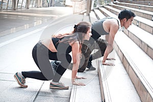 Young runner man and woman lover doing exercise together outside, partner buddy runner stretching body at staircase before run