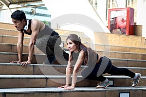 Young runner man and woman lover doing exercise together outside, partner buddy runner stretching body at staircase before run