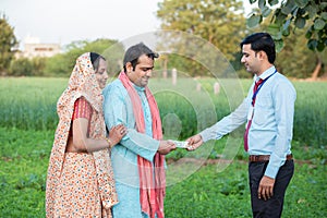 Young rural indian couple farmer receive money from banker at