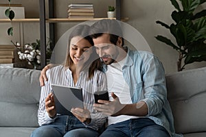Couple sit on sofa with modern diverse gadgets photo