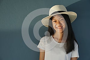 Young 11s kid girl smiling long hair with white hat with summer natural sunlight with blue wall background
