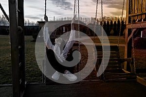 Young sad asian woman sitting on a swing in the evening.