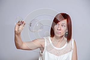 Young sad beautiful girl holding an empty transparent crystal inverted wine glass. Sommelier concept, finish wine, alcohol