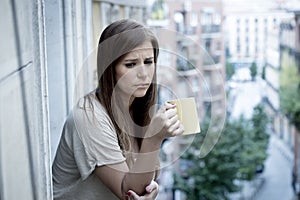 Young sad beautiful woman suffering depression looking worried and wasted on home balcony