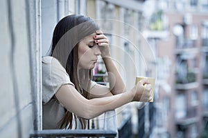 Young sad beautiful woman suffering depression looking worried and wasted on home balcony