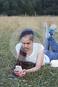 Young sad beautiful woman texting message on mobile phone in urban park - Teenager model girl with worried facial expression hold