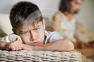 Young sad and bored Asian child at home couch feeling frustrated and unattended while mother networking on mobile phone as