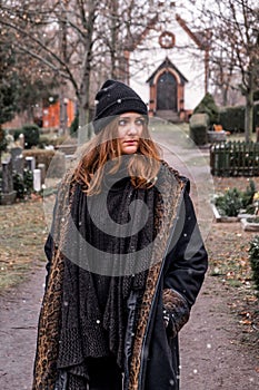 Young sad brunette woman walking alone in a cemetery