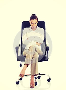 Young sad business woman sitting on a chair.