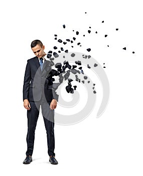 Young sad businessman shattering into small pieces on white background