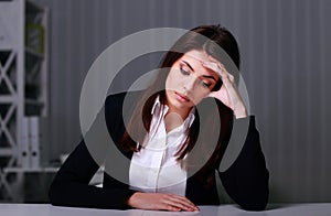 Young sad businesswoman sitting at the table on her workplace