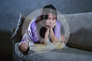 Young sad and depressed Asian Chinese woman crying alone desperate sitting at home sofa ouch worried in pain and stress suffering