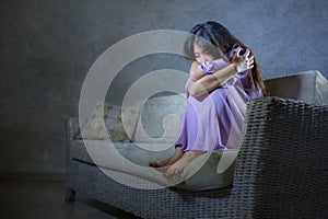Young sad and depressed Asian Korean woman crying alone desperate and worried in pain sitting at home sofa couch suffering depress