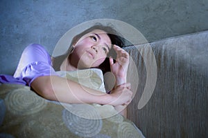 Young sad and depressed Asian Korean woman crying alone desperate and worried in pain sitting at home sofa couch suffering depress