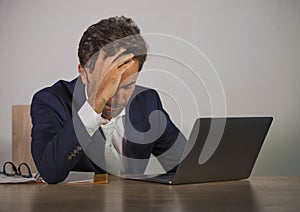 Young sad and depressed business man working overwhelmed and frustrated on laptop computer office desk feeling upset and stressed