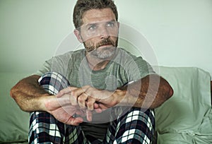 Young sad and depressed man lying thoughtful and pensive on bed looking away feeling lost thinking suffering some problem in