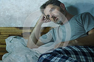 Young sad and depressed man lying thoughtful and pensive on bed looking away feeling lost thinking suffering some problem in