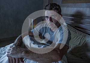 Young sad and depressed sleepless man lying on bed worried and thoughtful at home bedroom suffering depression problem feeling