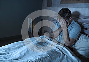 Young sad and depressed sleepless man lying on bed worried and thoughtful at home bedroom suffering depression problem feeling