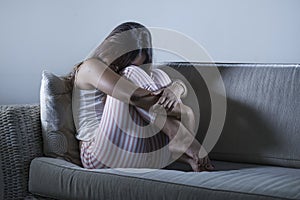 Young sad and depressed woman in pajamas at at home couch crying desperate feeling frustrated and upset suffering stress and