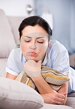 Young sad female lying on cozy sofa