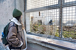 Young sad homeless woman depressed and abandoned standing on the street near ex building which is demolished for new apartments.