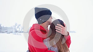 Young sad man hugging his wife. Emotional couple in love hugging at winter on snow background