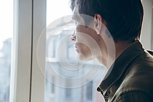 Young sad man looking out the window