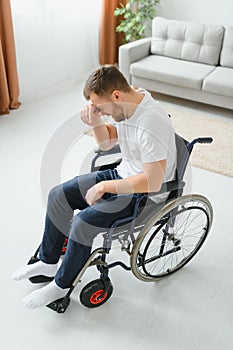Young sad man in a wheelchair at home
