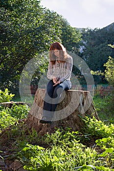 Young sad melancholic woman sit on big stub photo