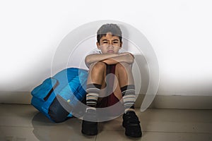Young sad scared kid 8 years old in school uniform and backpack sitting alone crying depressed and frightened suffering abuse prob