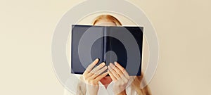 Young sad tired woman student covering her face with open book with blank cover