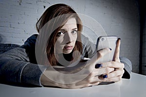 Young sad vulnerable girl using mobile phone scared and desperate suffering online abuse cyberbullying