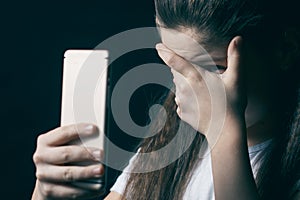 Young sad vulnerable girl using mobile phone scared and desperate suffering online abuse cyberbullying being stalked