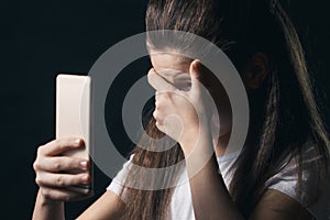 Young sad vulnerable girl using mobile phone scared and desperate suffering online abuse cyberbullying being stalked