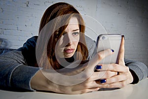 Young sad vulnerable girl using mobile phone scared and desperate suffering online abuse cyberbullying photo